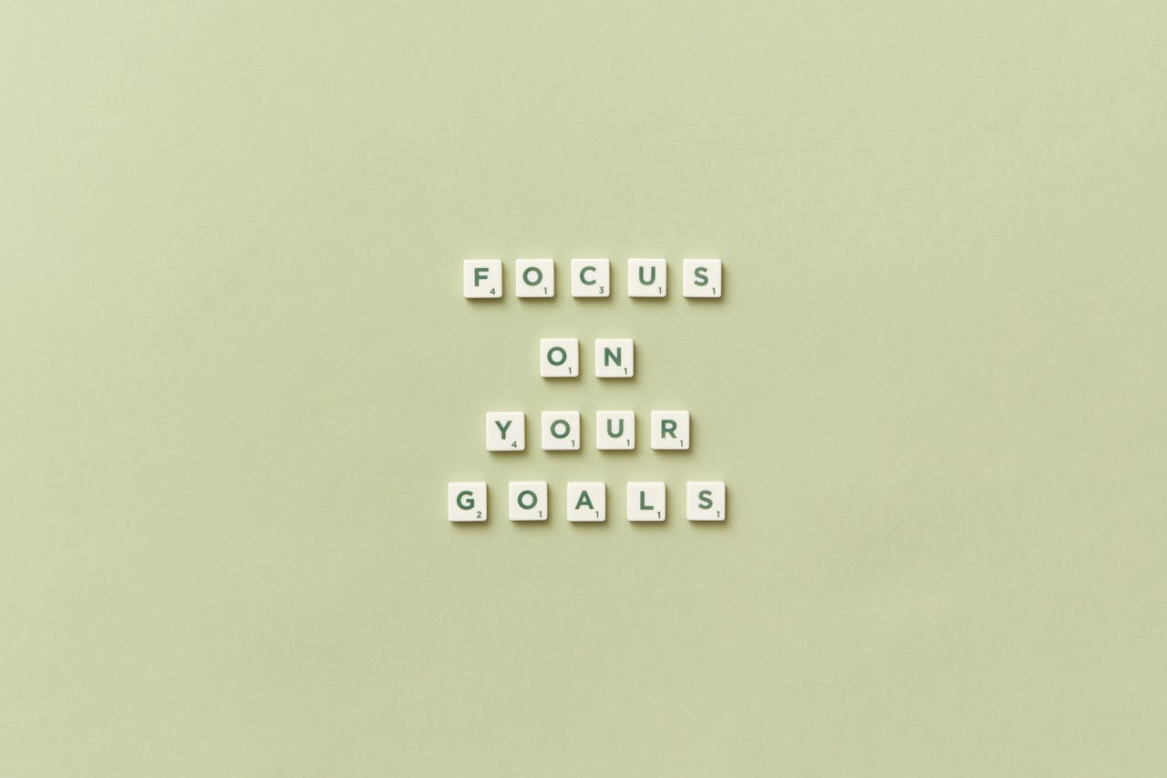 Scrabble letters forming a motivational phrase Focus on Your Goals on a light green background.